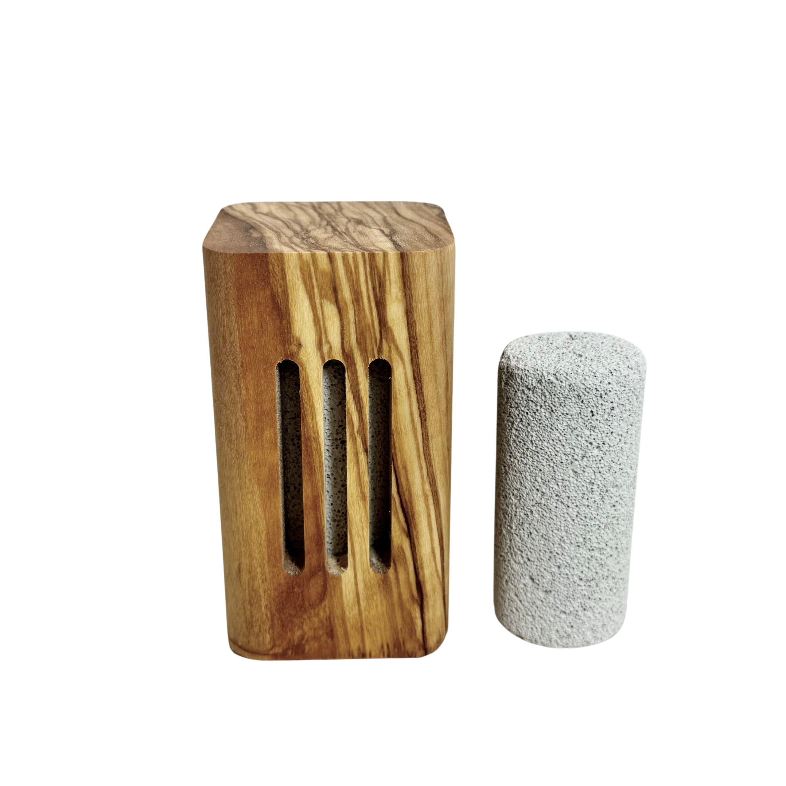 Ein rechteckiger Holzblock, welcher als Diffuser fungiert, mit dunkler Maserung und drei vertikalen Einlässen an der Seite zur Duftfreigabe. Rechts daneben befindet sich ein zylinderartiger Bimsstein.